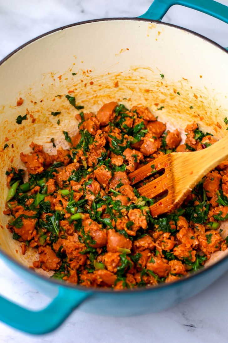 Vegan sausage and kale sautéed in a soup pot.
