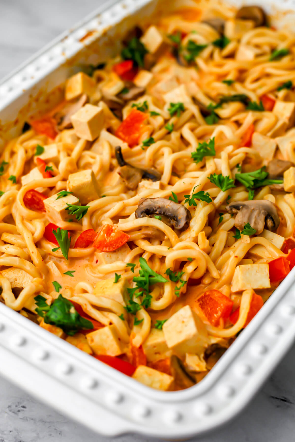 A casserole dish filled with vegan Thai red curry noodles with vegetables and tofu.
