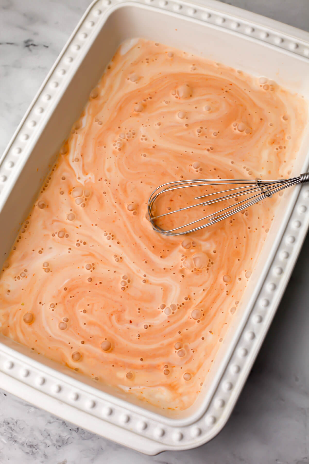 The red curry sauce mixing in the bottom of a casserole dish.
