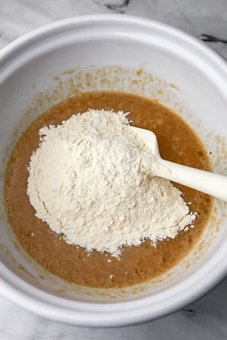 Flour added to the wet ingredients to make oat muffins.
