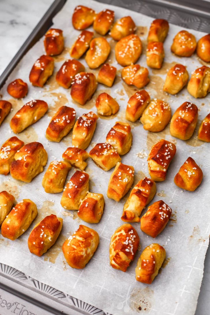 Vegan soft pretzel bites after they have baked on a sheet pan lined with parchment paper.