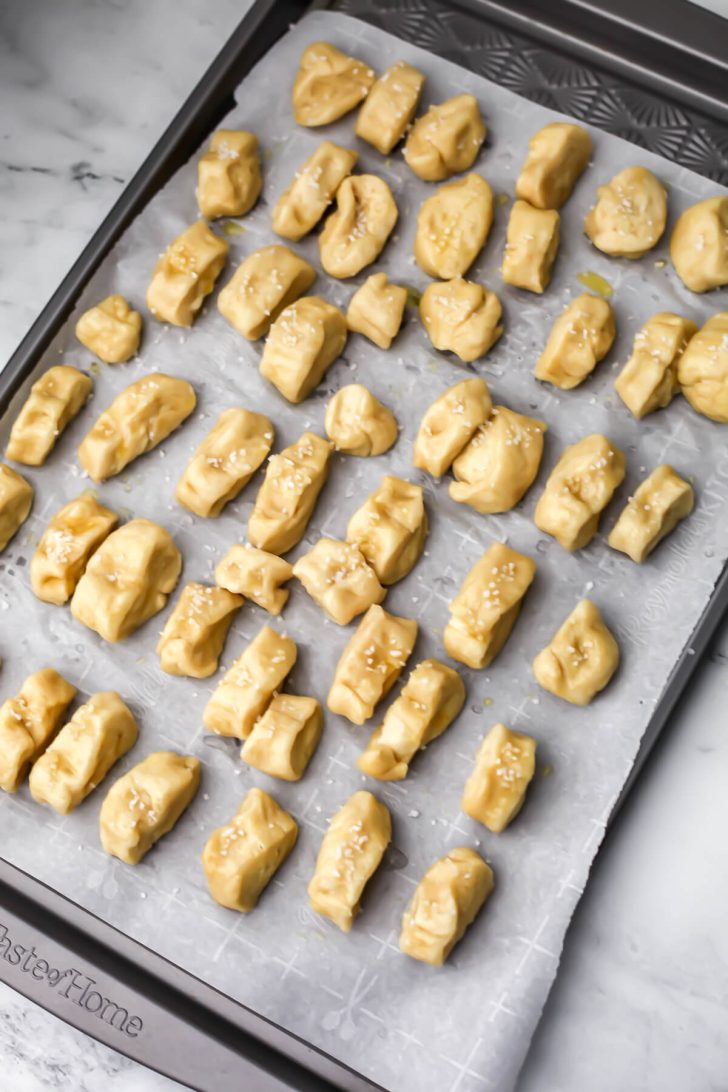 Vegan soft pretzel bites on a cookie sheet lined with parchment paper.