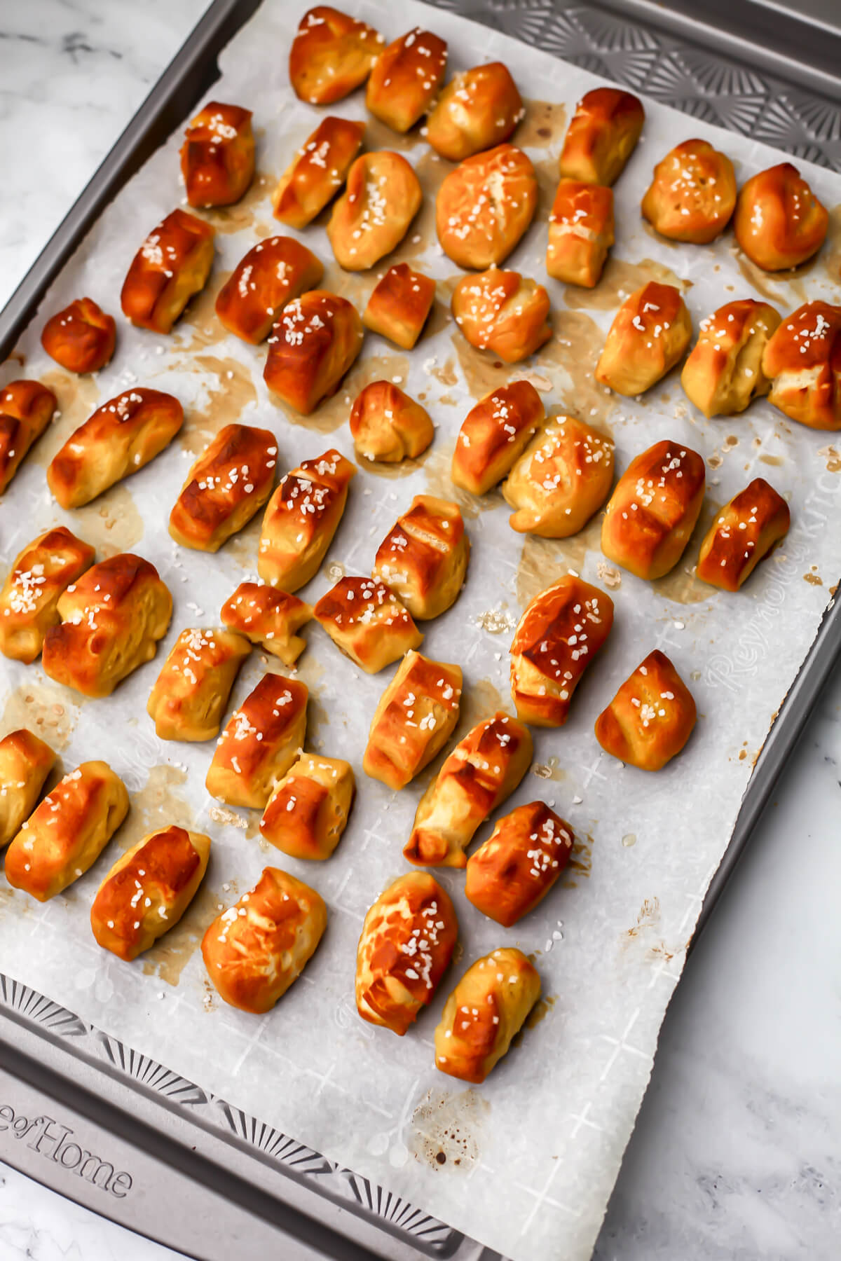 Vegan soft pretzel bites on a parchment lined cookie sheet after baking.