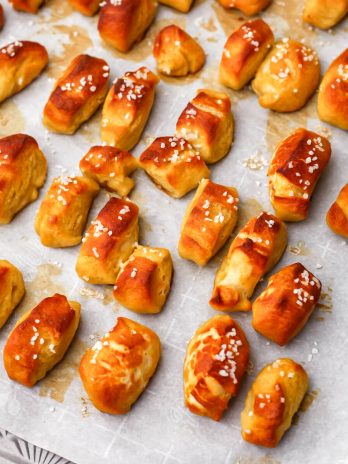 Vegan soft pretzel bites baked on a baking sheet covered with parchment paper.