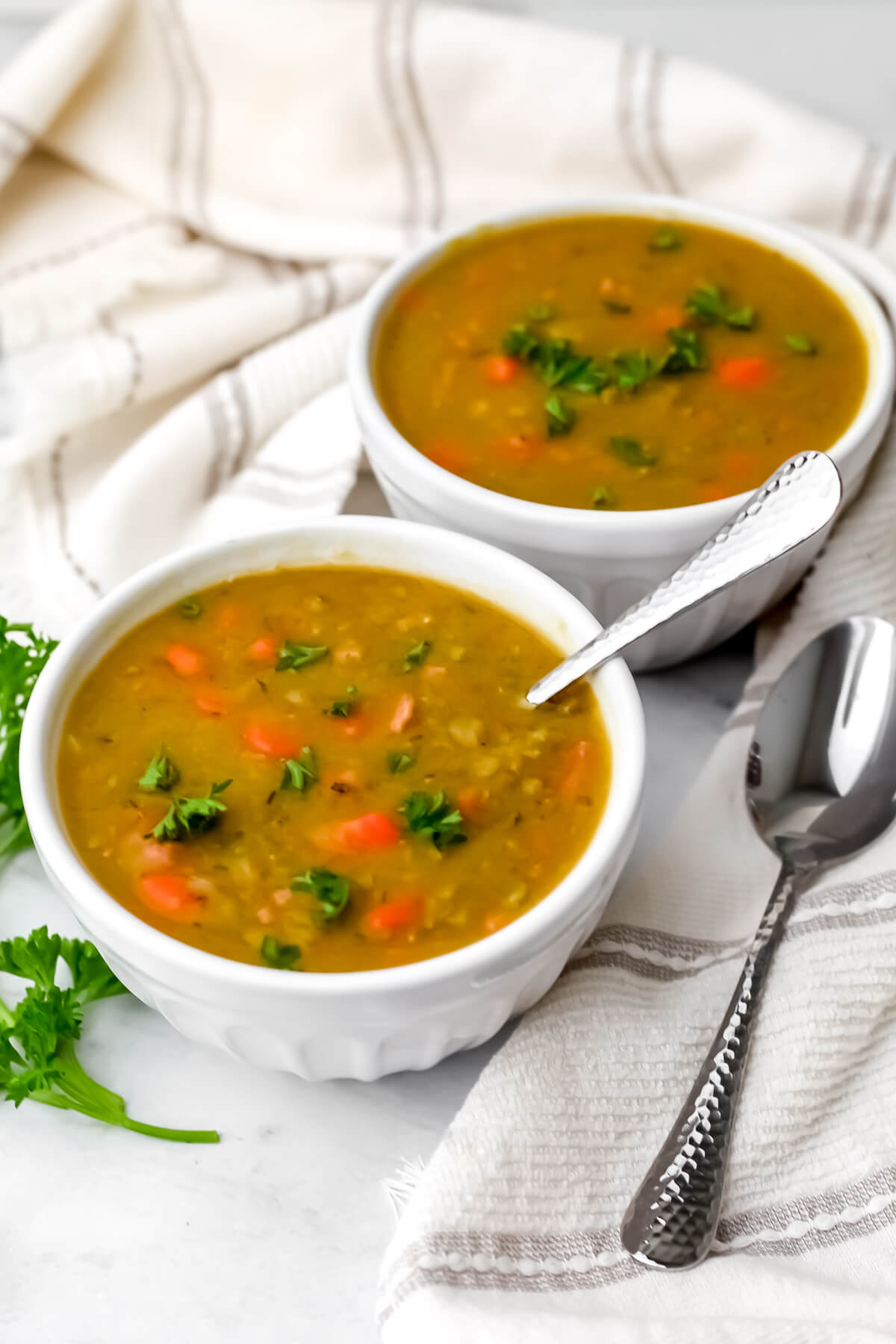 Two white bowls filled with vegan split pea soup.