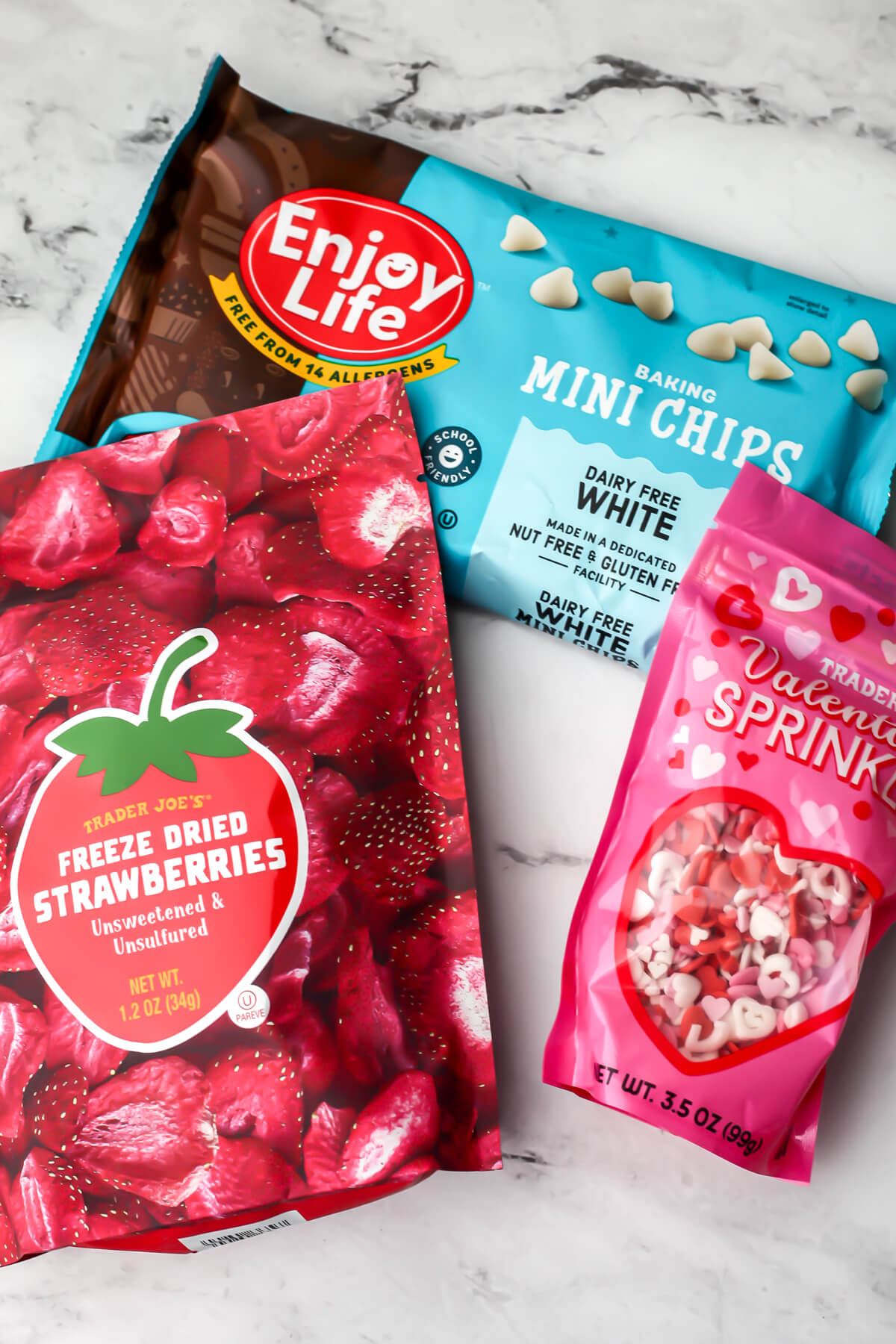 Vegan white chocolate chips, freeze dried strawberries, and vegan sprinkles to make vegan white chocolate bark.