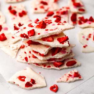 A close up of a pile of vegan white chocolate bark with dried strawberries and sprinkles.