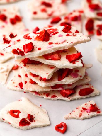 A close up of a pile of vegan white chocolate bark with dried strawberries and sprinkles.