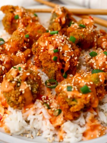 A plate of vegan bang bang broccoli served over white rice with chopsticks on the side.