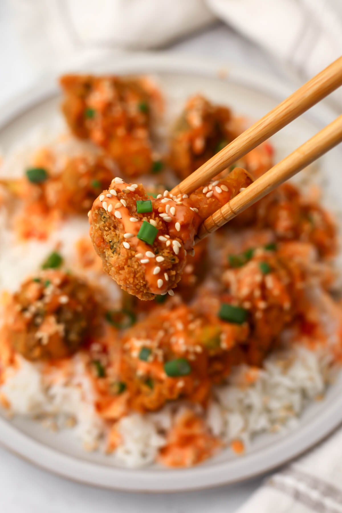 Someone picking up a piece of bang bang broccoli with chopsticks.