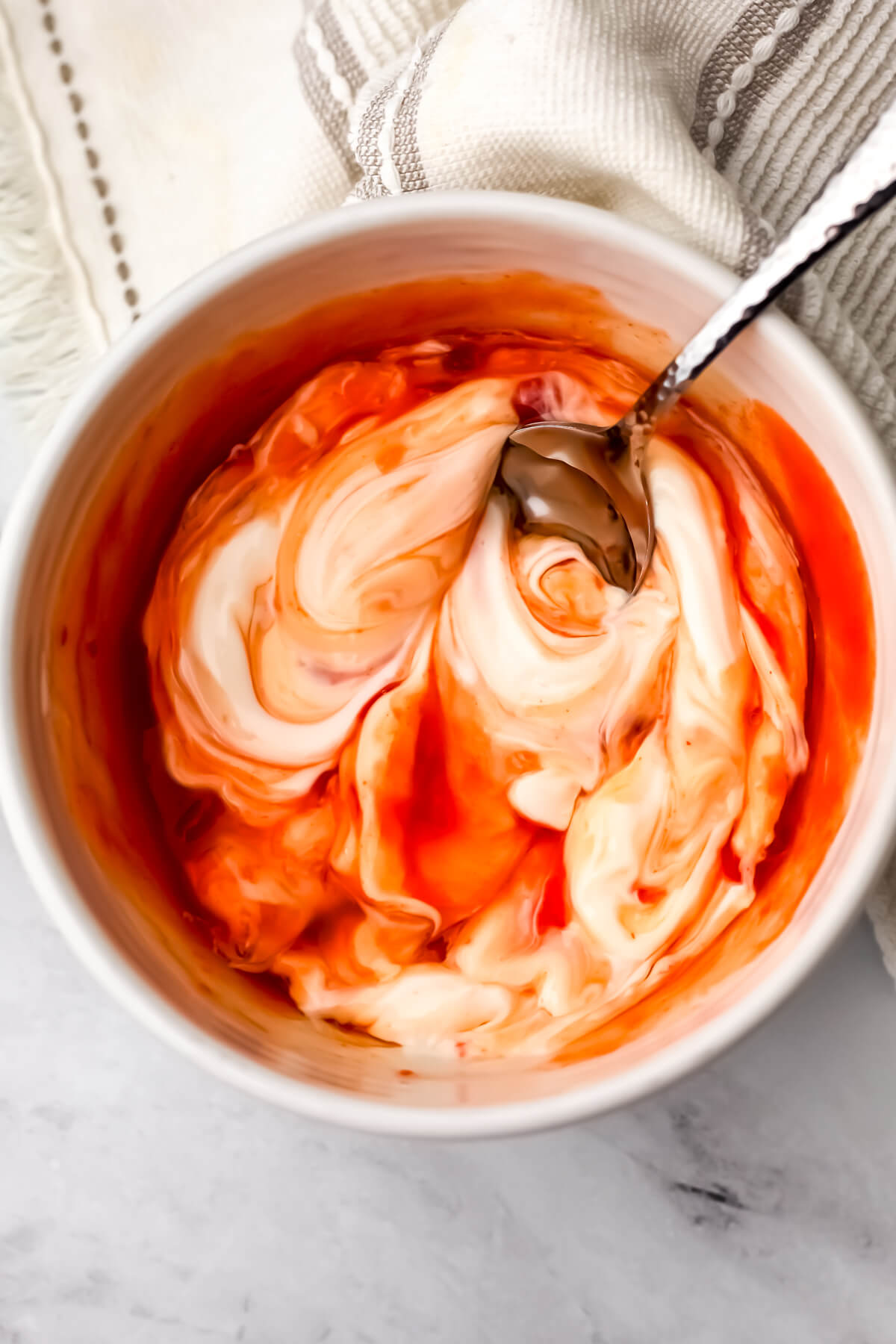 Vegan mayo, sweet chili sauce, sriracha, rice vinegar, and agave are being stirred up to make vegan bang bang sauce.