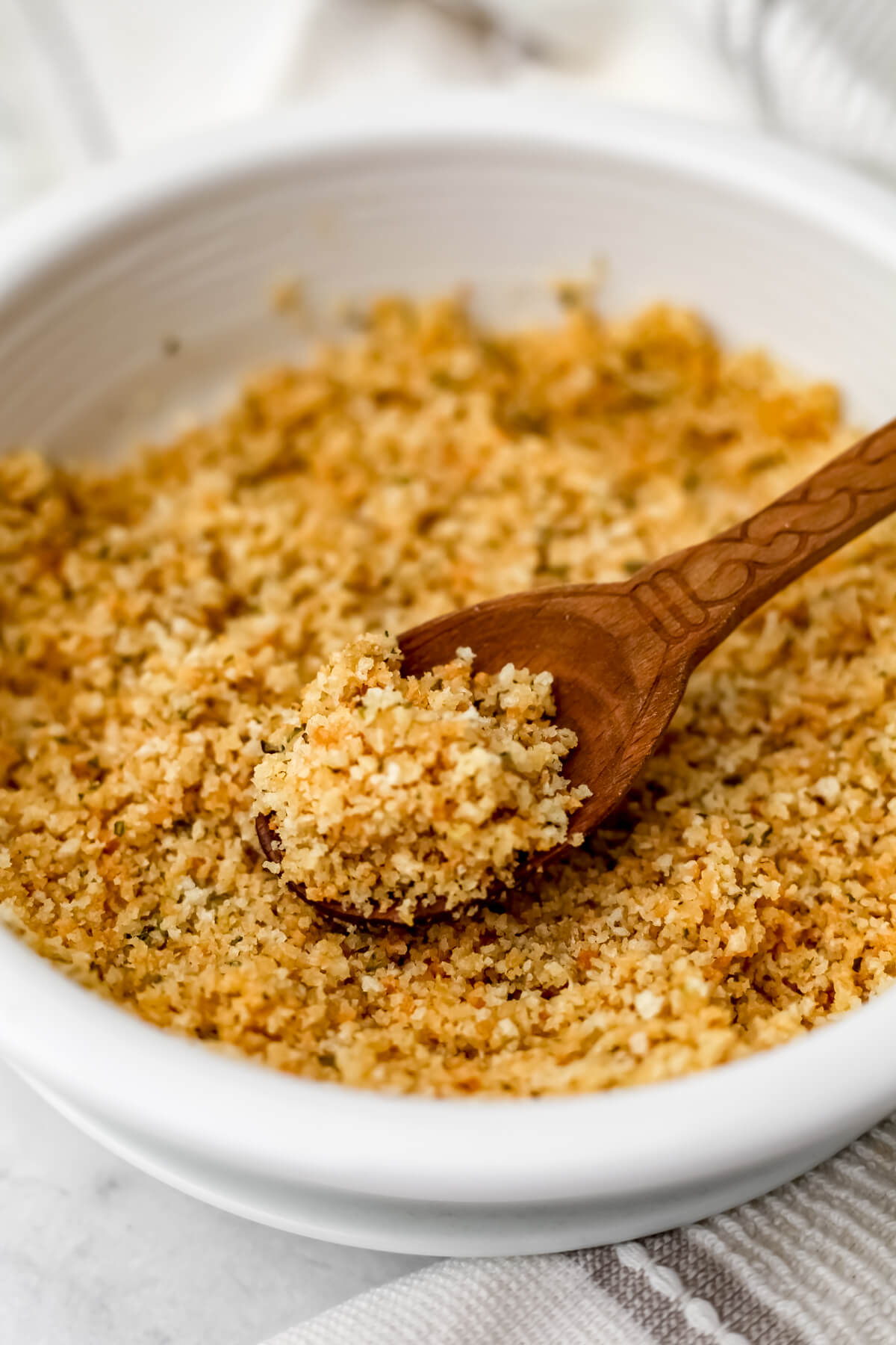 A white bowl of vegan breadcrumbs seasoned with garlic and Italian seasoning.
