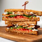 A Tofu BLT cut in half on a wooden cutting board.