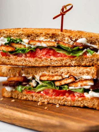 A Tofu BLT cut in half on a wooden cutting board.