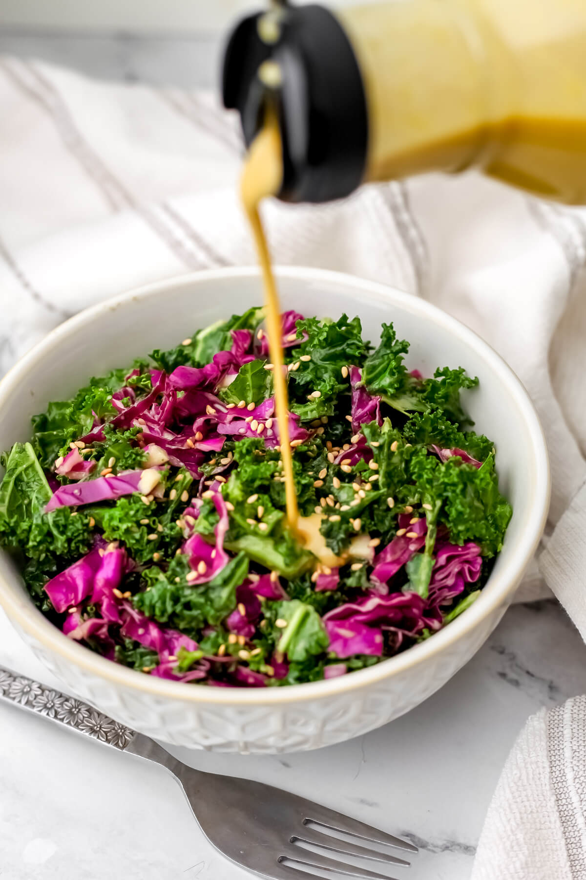 Nutritional yeast dressing being poured over a kale salad.