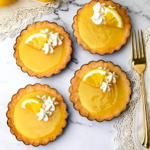 A top view of 4 vegan lemon tarts with a golden fork on the side.