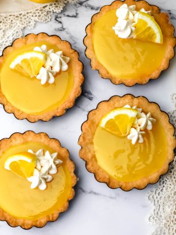 A top view of 4 vegan lemon tarts with a golden fork on the side.