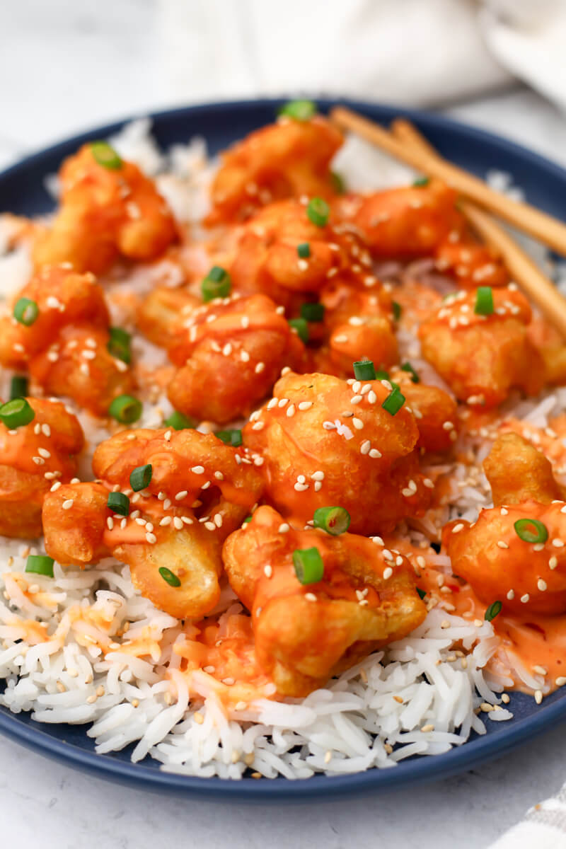 Vegan Bang Bang Cauliflower served over white rice on a blue plate.