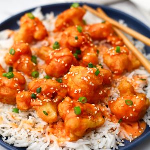A close-up of a plate full of white rice with bang bang cauliflower served over it.