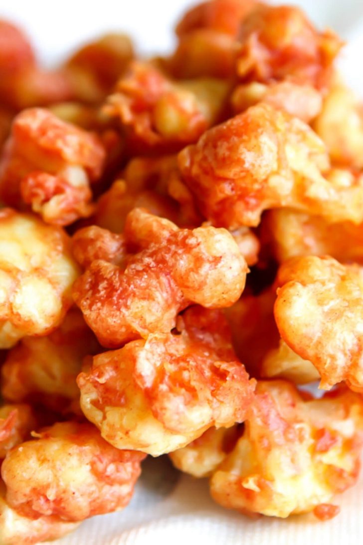 Battered and deep-fried cauliflower cooling on a paper towel.