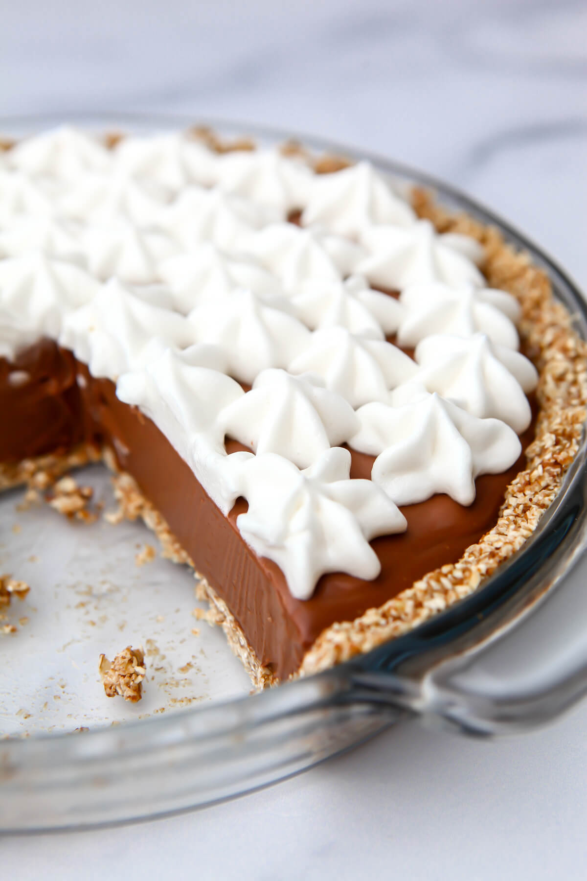 A vegan chocolate cream pie with a slice taken out of it.
