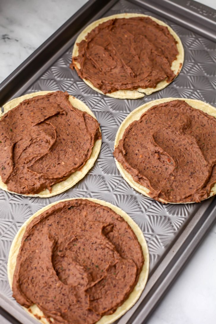 Black bean taco mixture spread on corn tortillas.