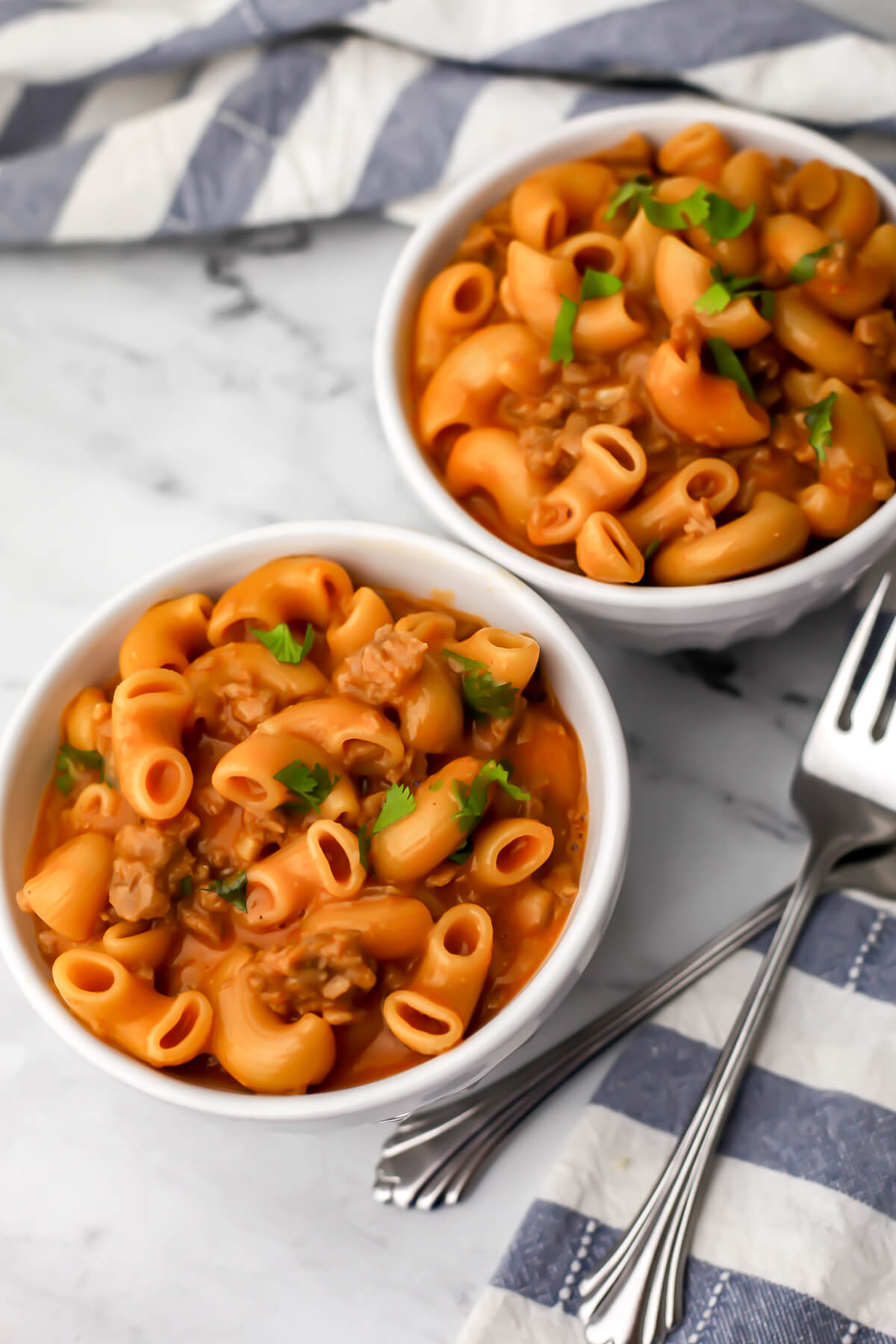 Two white bowls filled with vegan hamburger helper and garnished with parsley.