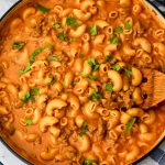 Vegan hamburger helper in a blue skillet being stirred with a wooden spoon.