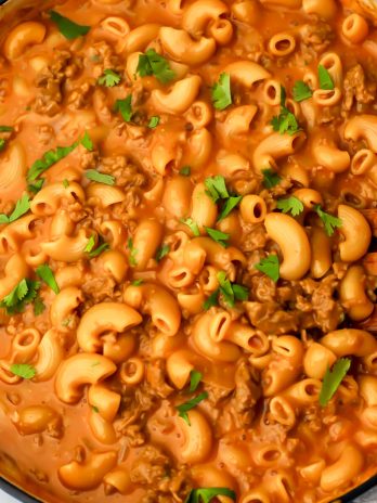 Vegan hamburger helper in a blue skillet being stirred with a wooden spoon.