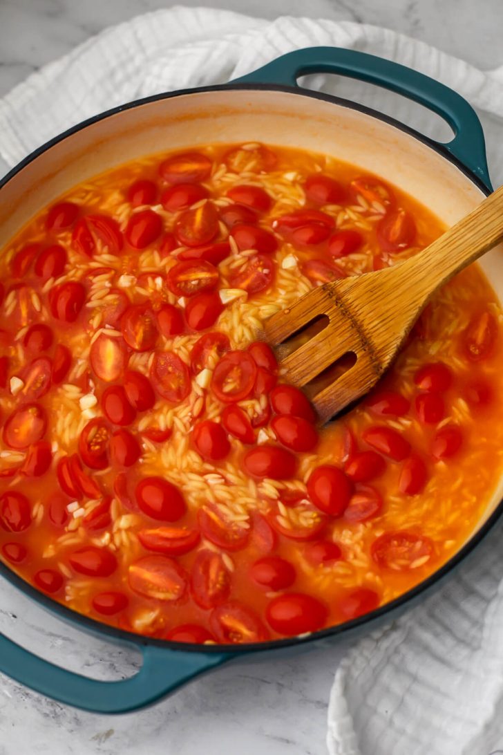 Orzo and water added to the cooked cherry tomatoes.