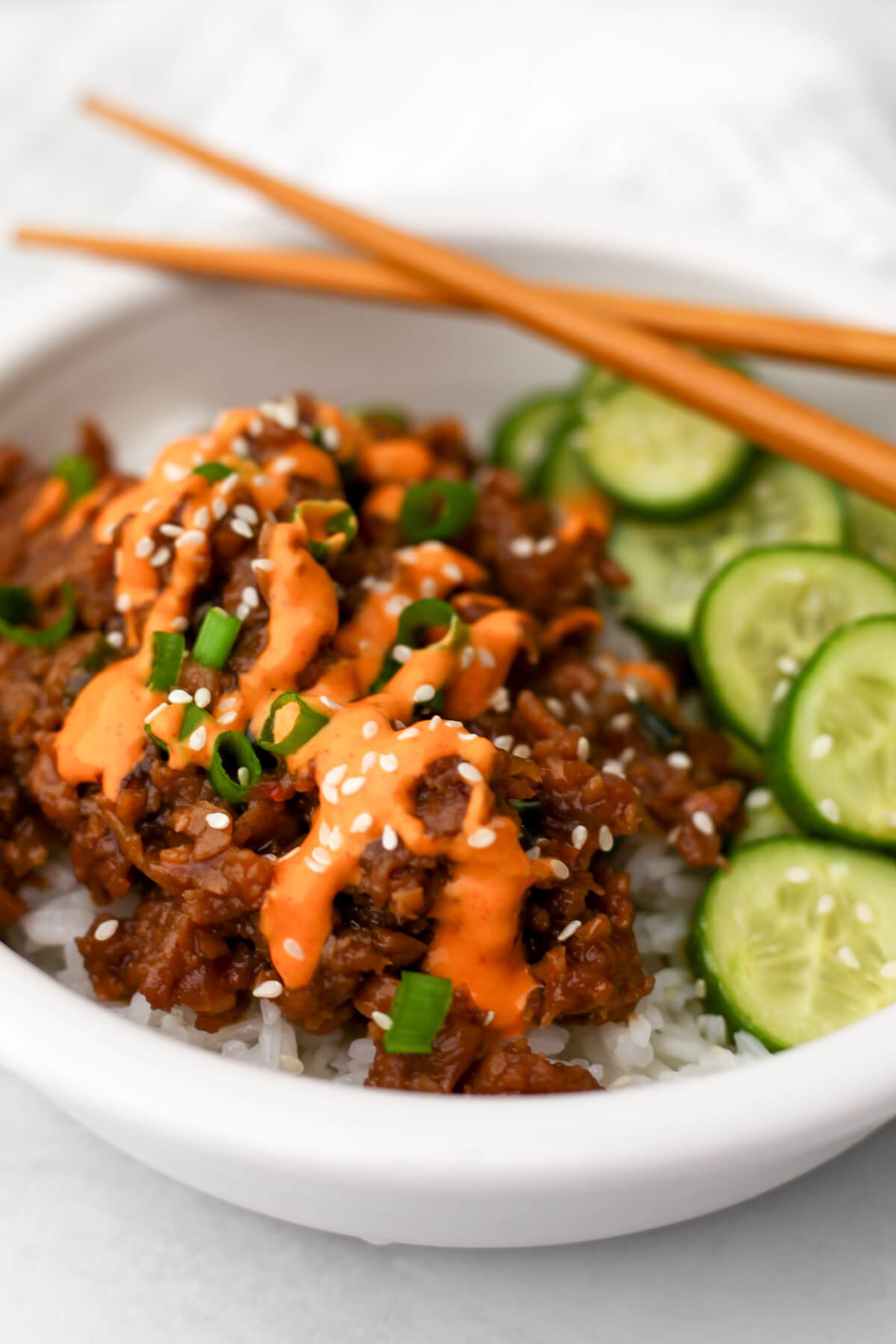Vegan Korean beef served over white rice with vegan yum yum sauce, green onions, and sesame seeds sprinkled on top.