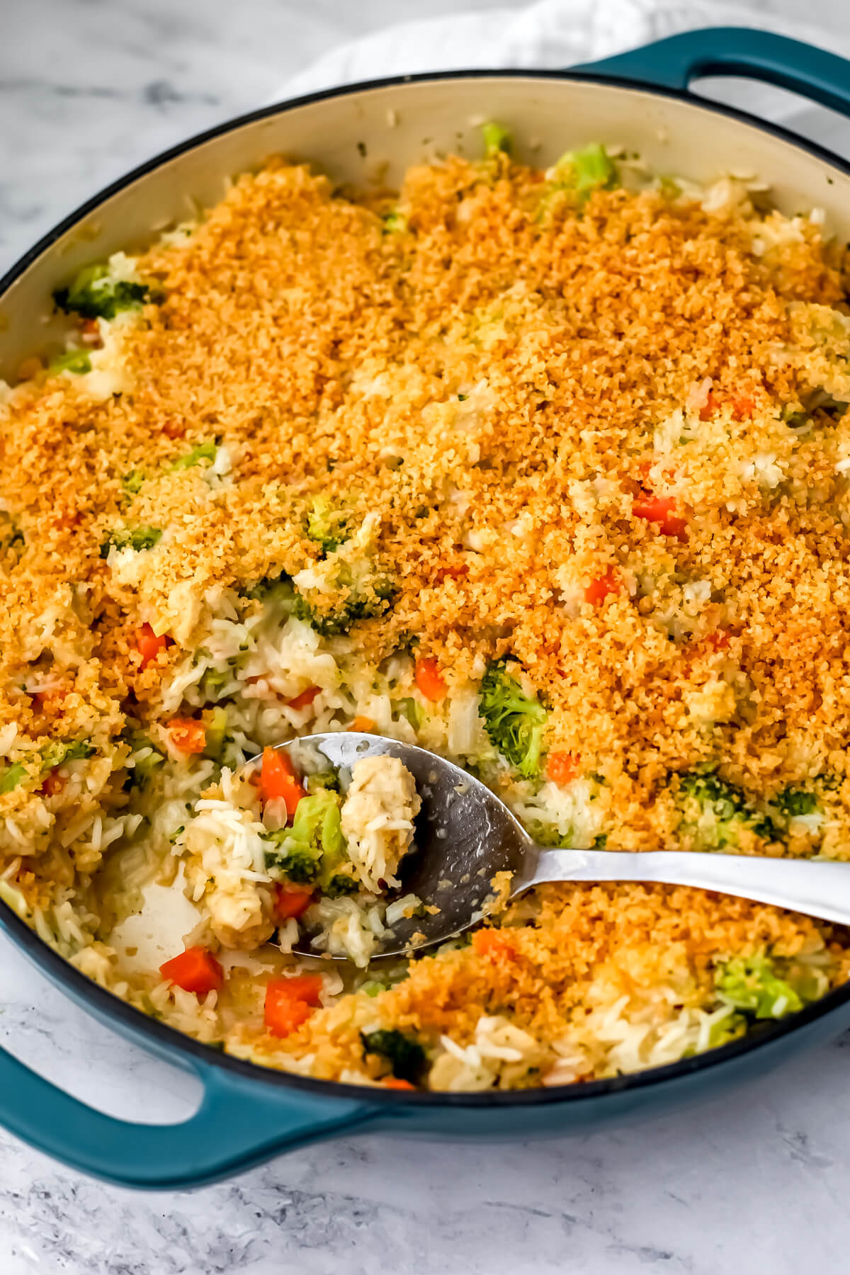 A blue skillet filled with a vegan chicken broccoli and rice meal topped with seasoned breadcrumbs.