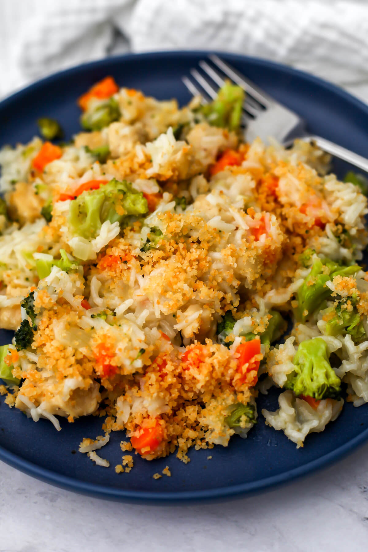 Vegan chicken broccoli and rice served on a blue plate with a fork on the side.