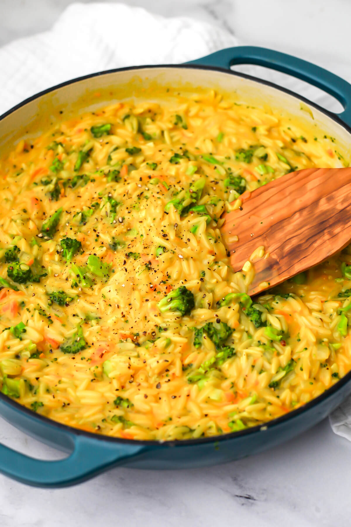 A top view of vegan broccoli cheddar orzo in a blue skillet.