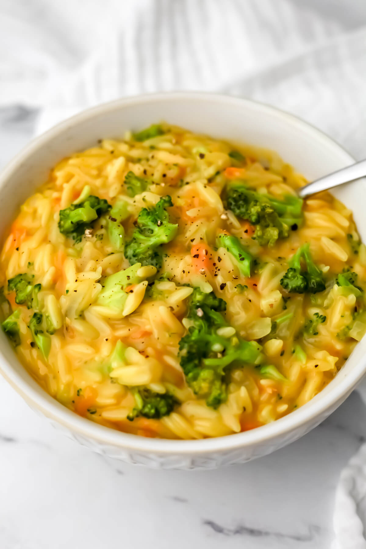 A white bowl full of vegan broccoli cheddar orzo.