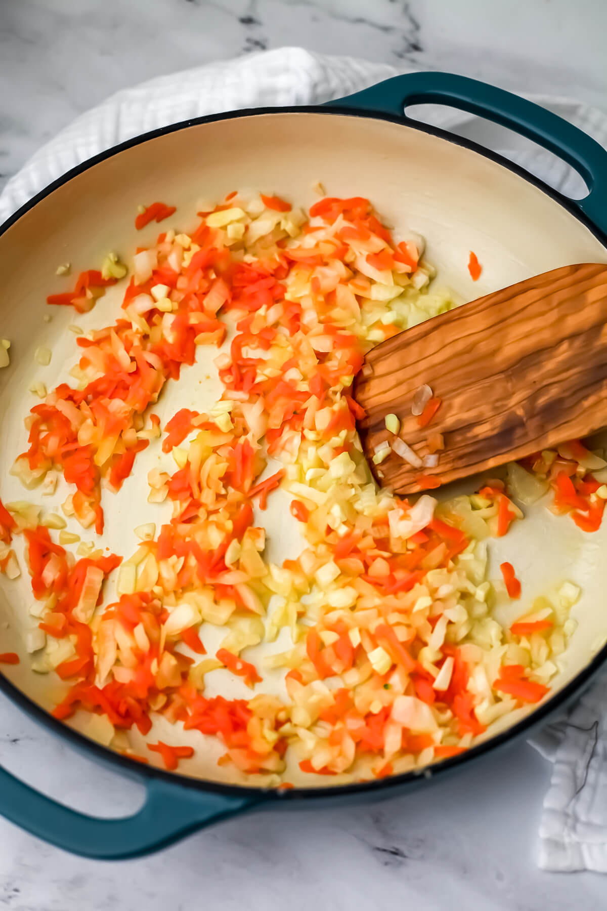 Onion and carrots cooking in a skillet to make broccoli cheddar orzo.