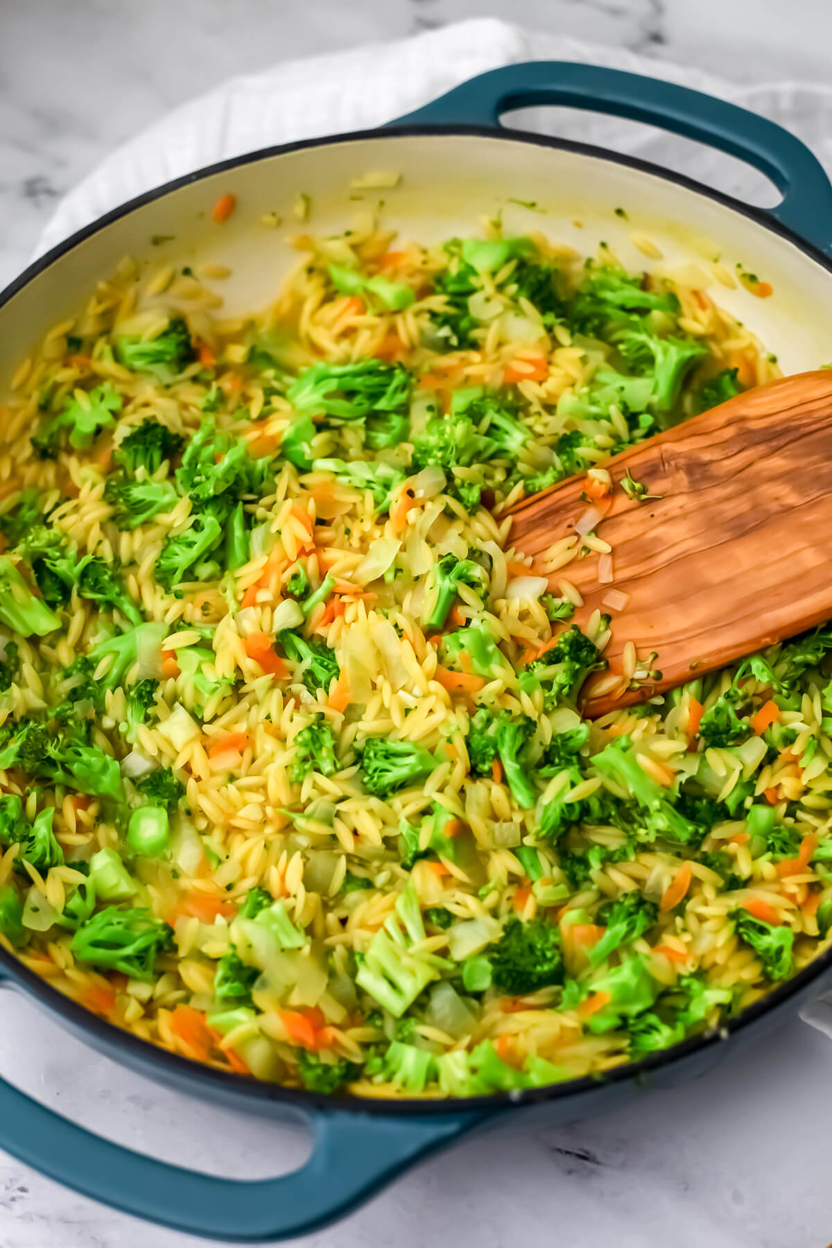 Small broccoli florets added to orzo in a skillet.
